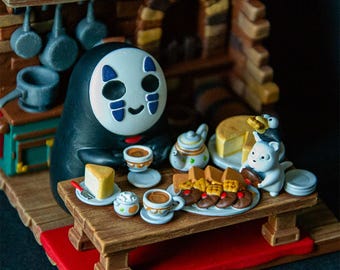以下が含まれることがあります： 千と千尋の神隠し のキャラクター、カオナシの白黒のフィギュアが、白い磁器のティーカップとソーサーを置いた木のテーブルに座っています。テーブルには、白いケーキ、クッキーの皿、小さなケーキの皿など、さまざまなペストリーとデザートが置かれています。フィギュアは、ティーカップとソーサーを手に持っています。