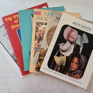 May include: A collection of five instructional craft booklets featuring smocking techniques and bonnet patterns. The front covers display various titles including The Pleasure of Smocking, Smocking Techniques, and Bonnets Pattern and 2 Designs by Barbie Beck, with photographic illustrations of children wearing bonnets.