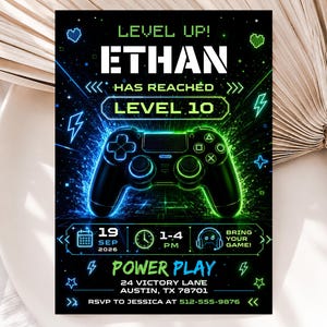 May include: A rectangular birthday invitation card featuring a black background with neon blue and green accents. The text reads LEVEL UP! ETHAN HAS REACHED LEVEL 10, with a central game controller graphic, date, time, location, and RSVP details.