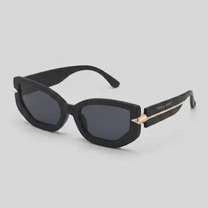 May include: Black sunglasses with a rectangular frame and dark lenses. The sunglasses have gold-colored accents on the temples and the text "FIFTH & NINTH" is printed on the left temple. The sunglasses are set against a light gray background.