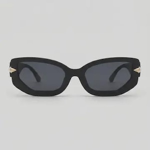 May include: Black sunglasses with a geometric frame and dark lenses. The sunglasses have gold-colored accents on the temples. The overall design is modern and stylish.