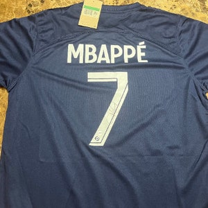Pode incluir: Uma camisa de futebol azul marinho com o nome "MBAPPÉ" e o número "7" impressos nas costas em branco.