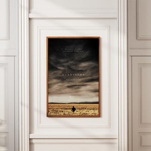Könnte beinhalten: Gerahmtes Filmplakat für "Gladiator" mit braunem Holzrahmen. Das Bild zeigt einen dramatischen Himmel über einem Feld mit einer Figur. Das Poster enthält die Namen Russell Crowe und Joaquin Phoenix.