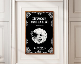 Puede incluir: Póster vintage enmarcado con el título "LE VOYAGE DANS LA LUNE" en texto blanco sobre fondo negro. El póster presenta una ilustración detallada de la luna con una cara y una nave espacial. El póster está en un marco de madera.