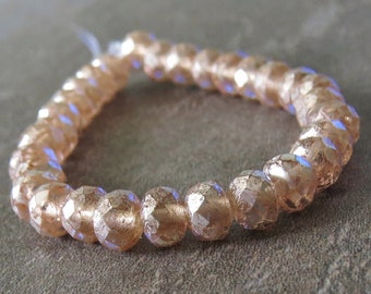May include: A strand of peach-colored glass beads with a faceted, iridescent finish. The beads are strung together to form a bracelet or necklace.