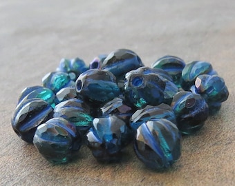 May include: A pile of dark blue glass beads with a ribbed texture. The beads have a slight iridescent sheen.