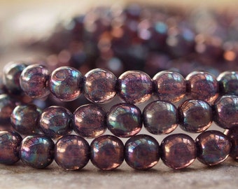 May include: A strand of iridescent purple glass beads. The beads are round and have a smooth, shiny finish.