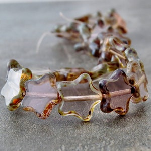 May include: A strand of star-shaped glass beads in shades of brown, green, and white. The beads are strung on a clear thread and have a slightly iridescent finish.