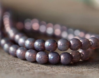 May include: A strand of iridescent purple glass beads. The beads are round and have a smooth, glossy finish.