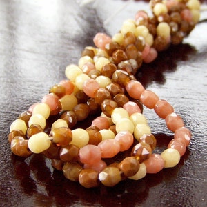 May include: A strand of multi-colored glass beads in shades of brown, cream, and pink. The beads are faceted and have a glossy finish.