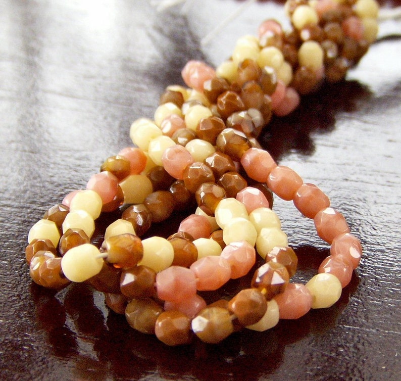 May include: A strand of multi-colored glass beads in shades of brown, cream, and pink. The beads are faceted and have a glossy finish.