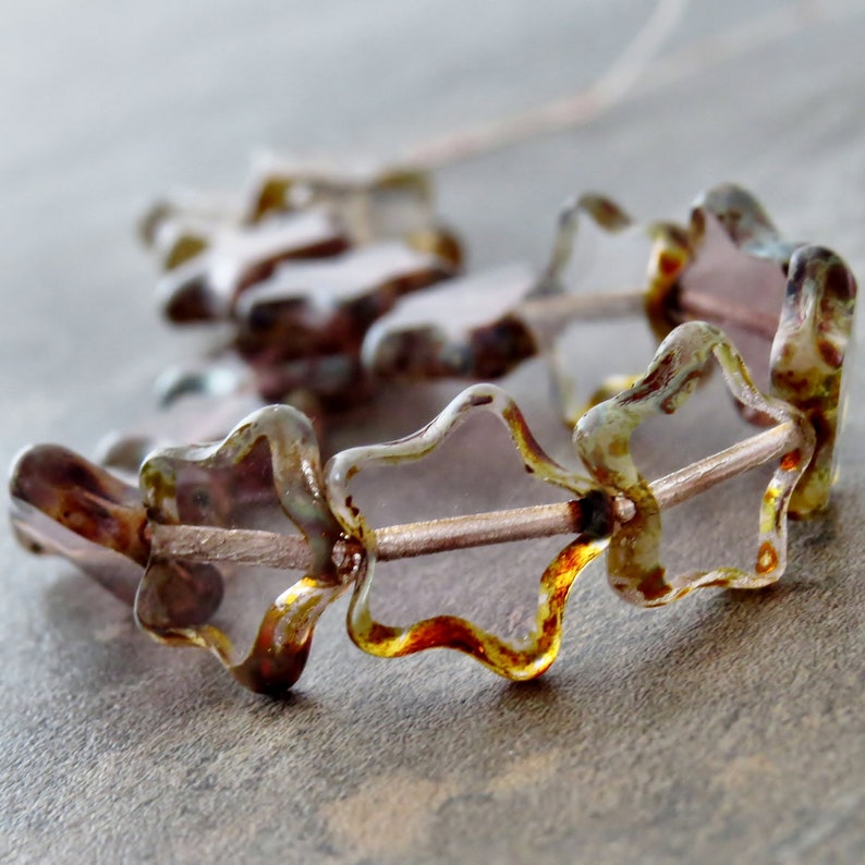 May include: A strand of star-shaped glass beads in brown, gold and clear colours.