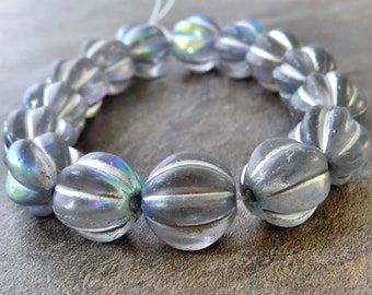 May include: A strand of iridescent glass beads with a ribbed texture. The beads are a light gray color with a subtle shimmer.
