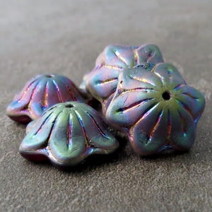 Peut inclure: Cinq perles en verre irisé dans des tons de violet, vert et bleu. Les perles sont en forme d'étoiles et ont une surface texturée.