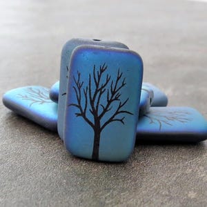 Könnte beinhalten: Ein Satz blauer und schwarzer rechteckiger Keramikperlen mit einem Baumdesign. Die Perlen sind irisierend und haben eine glatte, glänzende Oberfläche.