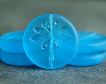 May include: Three round, light blue glass beads with a dragonfly design. The beads are stacked on top of each other.