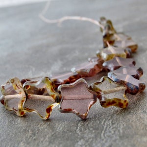 May include: A strand of star-shaped glass beads in shades of brown, pink, and clear. The beads have a mottled, textured surface.