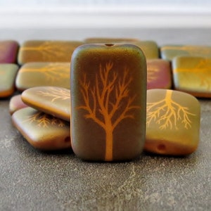 May include: A close-up of a stack of brown glass beads with an orange tree design. The beads are rectangular and have a glossy finish.