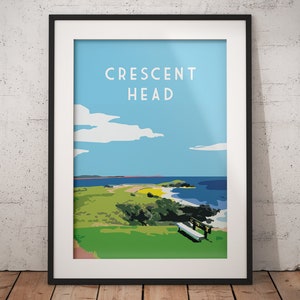 May include: A framed print of a colorful illustration of a landscape with a grassy hill, a beach, and a blue sky with clouds. The text "CRESCENT HEAD" is printed in white at the top of the image.