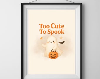 May include: Framed print with a cartoon ghost holding an orange pumpkin. The ghost has a smiling face and is surrounded by stars and a bat. The text "Too Cute To Spook" is written in orange above the ghost. A Halloween-themed illustration.