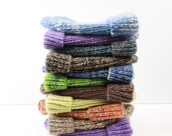 May include: A vertical stack of ten knitted beanies in various colors including light blue, purple, dark grey, brown, navy, lime green, tan, orange, and lavender. Each beanie features a ribbed cuff and a textured, multi-colored yarn knit.