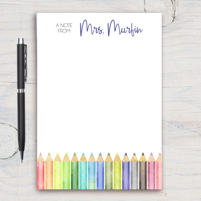 Puede incluir: Un bloc de notas con el texto "A Note From" y "Mrs. Murfin" en la parte superior. La parte inferior del bloc de notas presenta una fila de l&aacute;pices de colores.