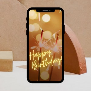 Puede incluir: Un tel&eacute;fono inteligente que muestra un saludo de cumplea&ntilde;os con el texto "Happy Birthday!" sobre un fondo de luces brillantes.