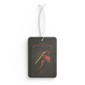 May include: Rectangular air freshener with a black background and a tarot card design. The card features a figure with a sword, a sun, and the text "0. DEATH BECOME MY BLADE, ONCE MORE". A white string is attached for hanging.