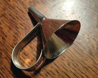 May include: A silver funnel with a long, narrow spout and a curved handle. The funnel is designed for pouring liquids into small openings.