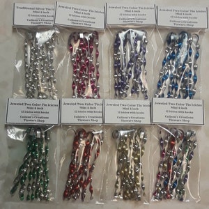 May include: Twelve packages of silver and multi-colored tin icicle ornaments, each package containing 12 icicles with hooks. The icicles are 4 inches long and are sold by Colleen's Creations Tinware Shop.