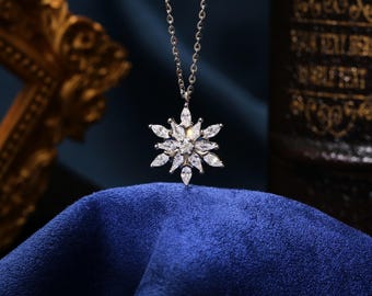 May include: A silver snowflake pendant necklace with clear cubic zirconia stones. The necklace is on a blue velvet surface.
