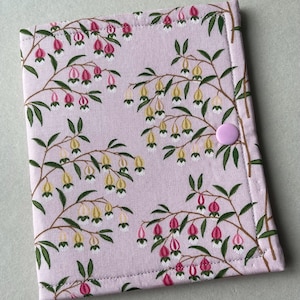 May include: A light purple fabric case with a floral pattern of pink and yellow bell-shaped flowers and green leaves. The case has a light purple button closure.