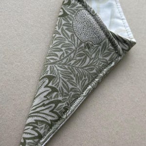 May include: A triangular fabric pouch featuring a sage green and white botanical print with stylized leaves and fruit motifs. The exterior is constructed from patterned cotton fabric, while the interior is lined with a plain white fabric.