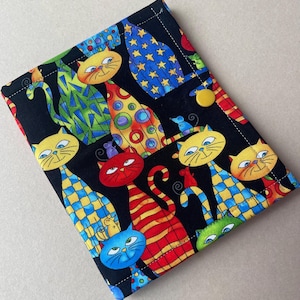 May include: A black fabric case with a colorful cat pattern. The cats are in various colors and patterns, including yellow, blue, red, and green, with a button closure. The case is likely for a tablet or e-reader.