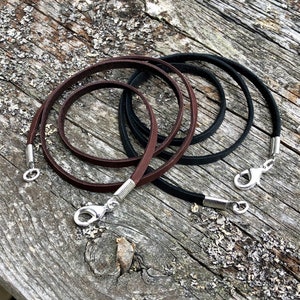 May include: Two leather cords with silver clasps. One cord is brown and the other is black.