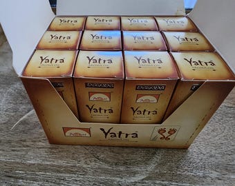 May include: A cardboard box filled with small, brown boxes of Yatra Aroma Oil. Each box has the word "Yatra" in a stylized font. The box also features the Parimal logo and the words "Aroma Oil".