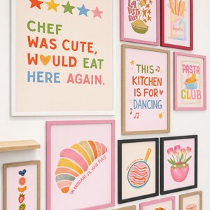 May include: A collection of framed art prints with colorful illustrations and text. Prints include phrases like "Chef Was Cute, Would Eat Here Again" and "This Kitchen Is For Dancing." Other prints feature food items like pasta, croissants, and baguettes.