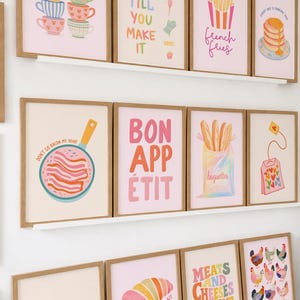 May include: A collection of framed art prints with a food theme. The prints feature illustrations of tea cups, bacon, French fries, pancakes, strawberries, croissants, baguettes, and chickens. Text includes "Tea time?", "Bake it till you make it", "French fries", "Bon app&eacute;tit", and "Meats and cheeses always pleases".