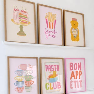 May include: Six framed art prints with food-themed illustrations. Prints include a cake, French fries, a bear, stacked teacups with "Tea time?" text, pasta with "Pasta Club" text, and "Bon App&eacute;tit" text.