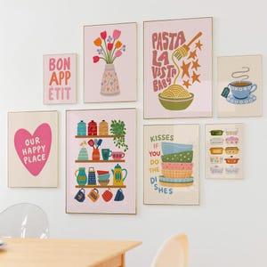 May include: A collection of framed art prints with gold frames. The prints feature colorful illustrations of kitchen items, food, and phrases like "Bon Appetit" and "Pasta La Vista Baby." The art has a whimsical, retro style.