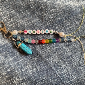 May include: A colorful beaded keychain with the name "WHOVIAN" spelled out in white letters. The keychain also features a turquoise crystal charm.