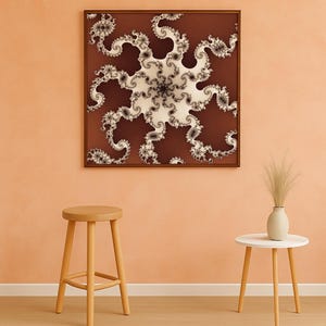 Op de afbeelding: Een ingelijste abstracte fractalkunstprint in tinten bruin, wit en zwart hangt aan een perzikroze muur. Een houten kruk en een kleine witte bijzettafel met een vaas met gedroogd gras staan op de voorgrond.