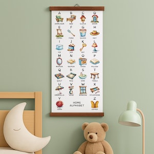 Op de afbeelding: Een educatieve poster met houten frame, met het alfabet en bijbehorende illustraties. Elke letter heeft een bijbehorende afbeelding, zoals een fauteuil voor A en een bed voor B. De poster is getiteld "HOME ALPHABET".
