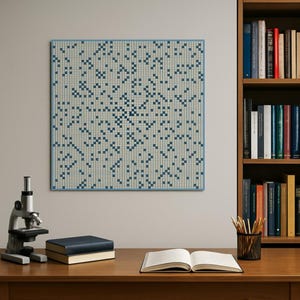 May include: A square wall art piece with a blue border features a pattern of small, dark blue squares on a light beige background. The artwork hangs on a light gray wall above a wooden desk. A microscope, books, and an open notebook are on the desk.