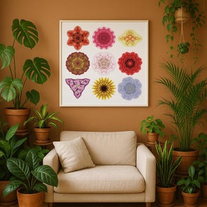 Op de afbeelding: Een ingelijste print met negen kleurrijke, symmetrische bloemmotieven. Het kunstwerk hangt boven een beige bank, omringd door potplanten in terracotta potten. De muur is geschilderd in een warme bruine kleur.