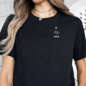 May include: A black t-shirt with a white graphic that says "Be you-tiful" with a bee and a heart.