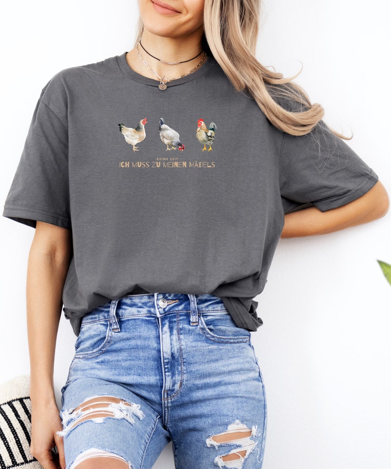 May include: A grey t-shirt with a graphic of three chickens and the text "Keine Zeit, ich muss zu meinen M&auml;dels".