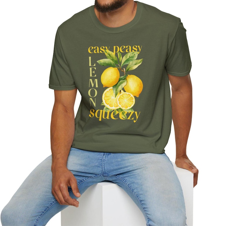 May include: Olive green t-shirt with a watercolor illustration of lemons and leaves. The text "easy peasy lemon squeezy" is printed in yellow. The shirt is short-sleeved and has a crew neck.