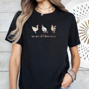 May include: Black t-shirt featuring a graphic of three chickens and a rooster. The text "Keine Zeit Ich Muss Zu Meinen M&auml;dels" is printed below the graphic.