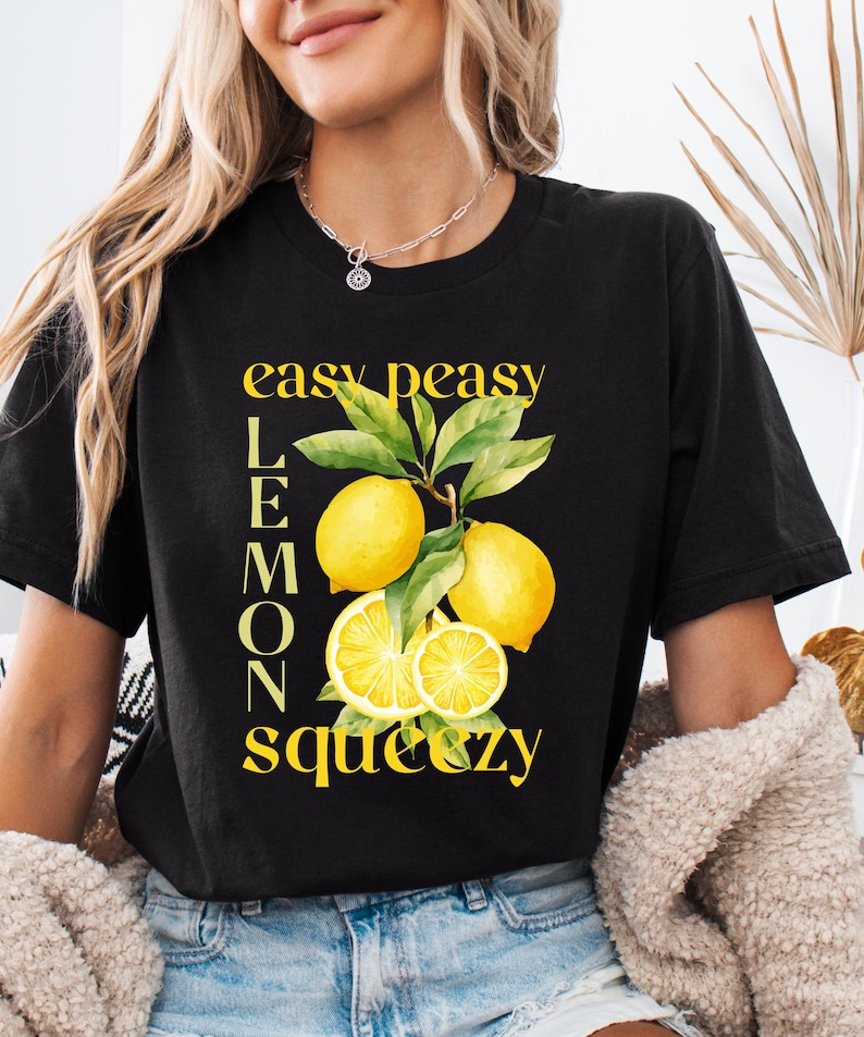 May include: Black t-shirt with a yellow lemon graphic and the text "easy peasy lemons squeezy". The graphic features whole and sliced lemons with green leaves. The shirt is a casual style.